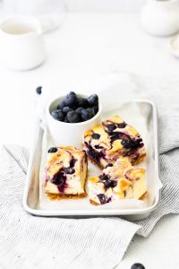 3 Gluten Free Blueberry Cheesecake Bars on a parchment paper lined 1/8 sheet pan