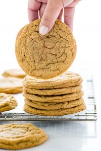 a hand picking up a Gluten Free Brown Sugar Cookie from a stack of cookies on a wire rack