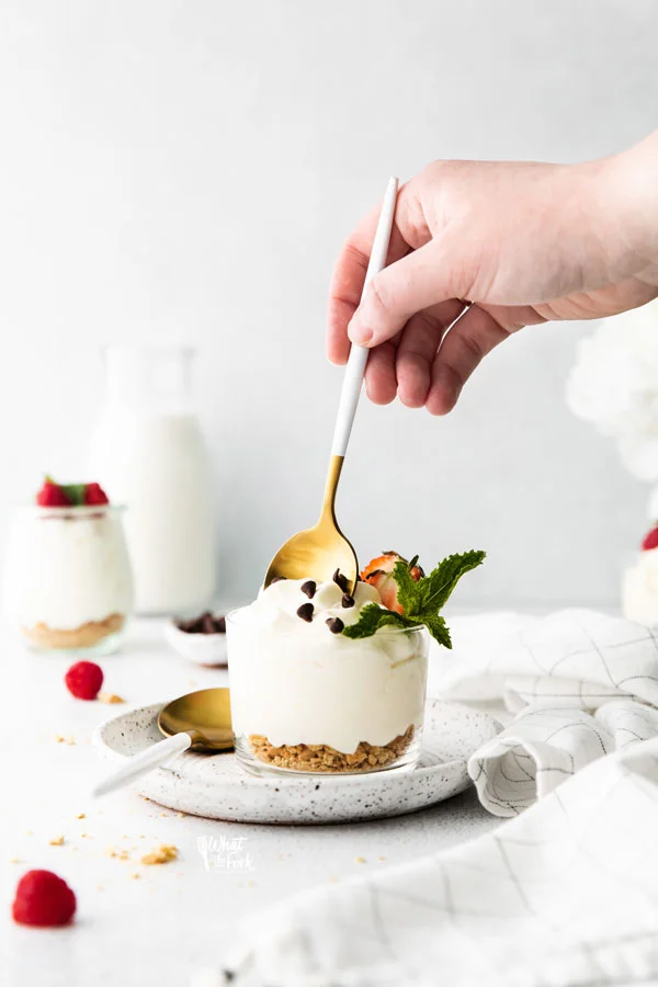 a gold and white spoon being dipped into a serving dish of Cheesecake Mousse