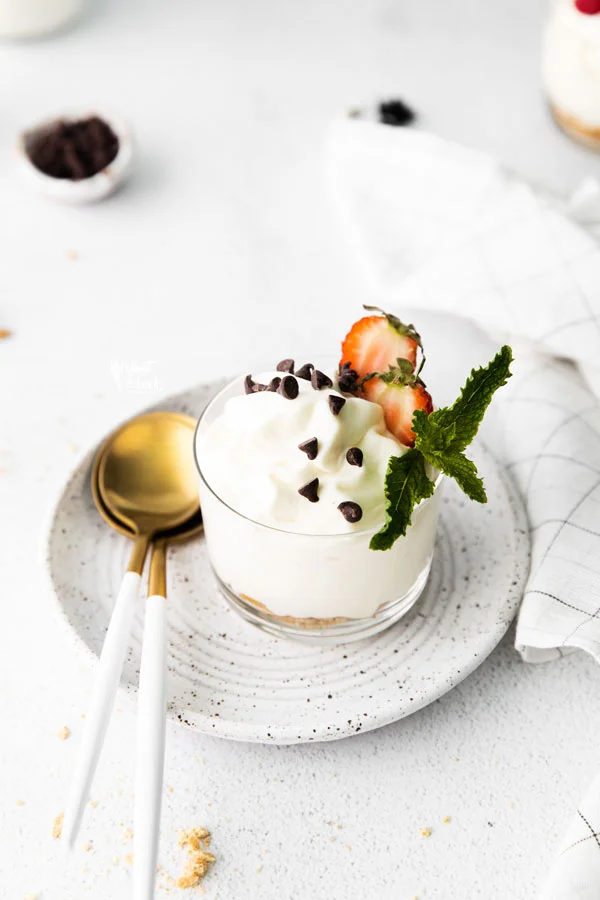 gluten free Cheesecake Mousse in an individual serving dish on a pottery plate with a gold spoon on the side