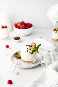 Cheesecake Mousse in a glass bowl on a pottery plate with gold and white spoons