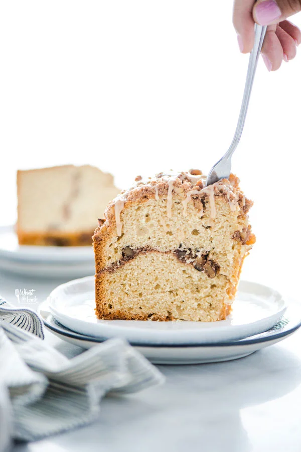 a slice of gluten free sour cream coffee cake on a plate with a fork taking a piece out