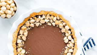 overhead shot of a Macadamia Nut Chocolate Pie with Coconut Crust on a blue and white striped cloth napkin