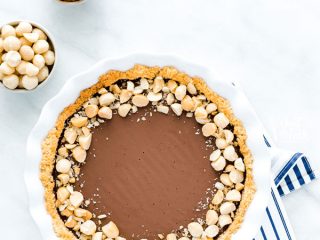 overhead shot of a Macadamia Nut Chocolate Pie with Coconut Crust on a blue and white striped cloth napkin