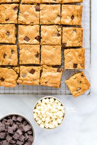overhead shot of gluten free blondies on a cooling rack with bowls of white chocolate chips and chocolate chunks