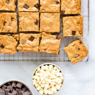 overhead shot of gluten free blondies on a cooling rack with bowls of white chocolate chips and chocolate chunks
