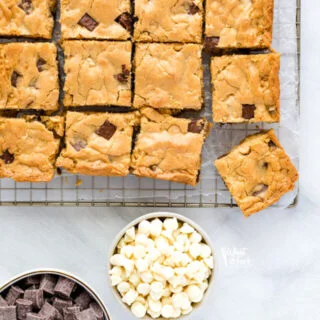overhead shot of gluten free blondies on a cooling rack with bowls of white chocolate chips and chocolate chunks