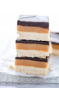 a stack of 3 Gluten Free Millionaire Shortbread bars on a small wire rack