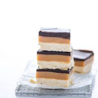 a stack of 3 Gluten Free Millionaire Shortbread Bars on a small wire rack lined with wax paper