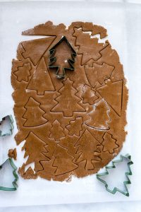 overhead shot of gluten free gingerbread cookie dough rolled out and cut with Christmas tree cookie cutters