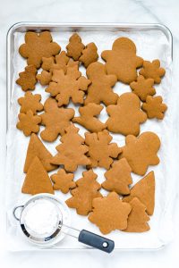 overhead shot of gluten free gingerbread cookies on a parchment paper lined baking sheet