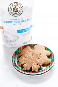 Gluten Free Gingerbread Cookies on a red and green plaid plate with a bag of King Arthur Gluten Free Measure for Measure Flour in the background
