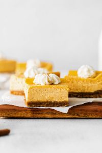 straight on shot of Gluten Free Pumpkin Cheesecake Bars topped with whipped cream