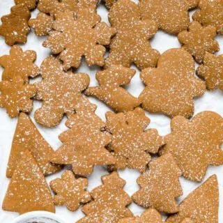 overhead shot of gluten free gingerbread cookies on a parchment paper lined baking sheet dusted with parchment paper