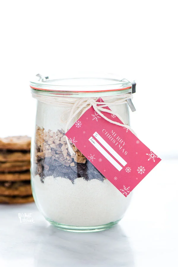 ingredients to make a Gluten Free Christmas Cookie Jar layered in a class jar with a red gift tag attached