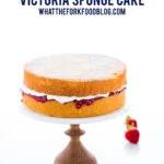 gluten free Victoria Sponge Cake on a marble cake stand with a wood base. Image includes text for Pinterest