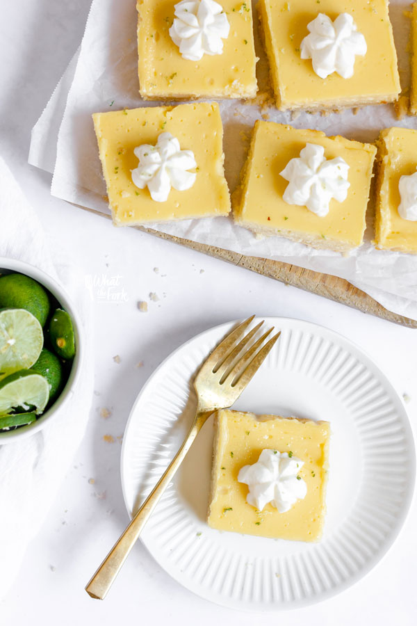 overheard shot of a gluten free key lime pie bar on a small white plate with a gold fork