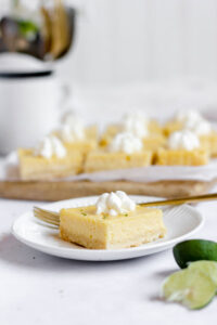 sliced gluten free key lime pie bars ready to serve with one piece on a small round white plate