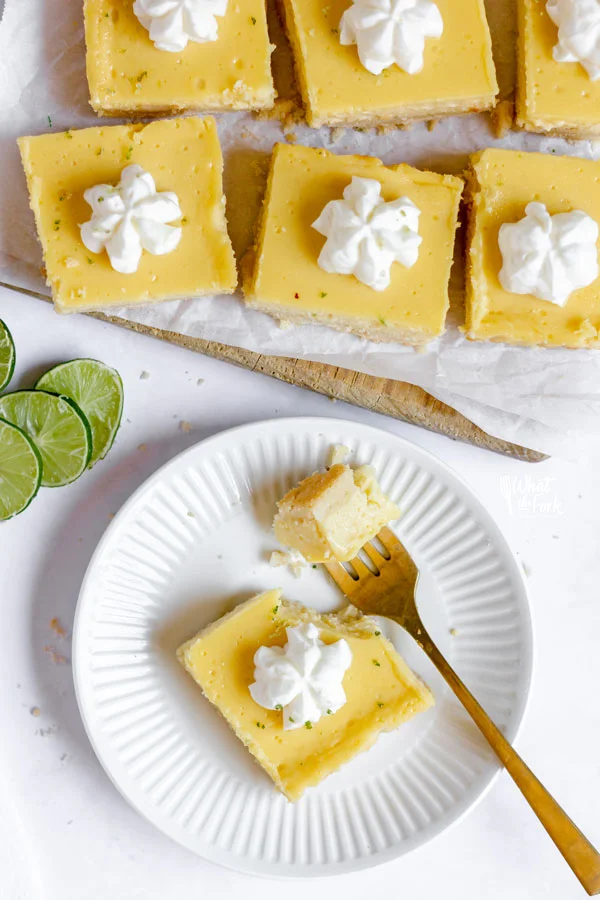 overhead shot of a gluten free key lime pie bar on a small round white plate with a bite-sized piece on a gold fork