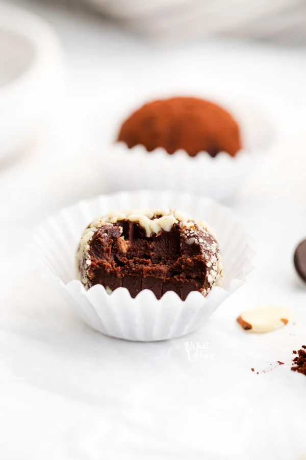 An Amaretto Truffle rolled in Minced Almonds in a white paper liner with a bite taken out