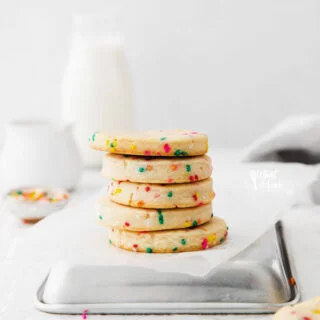 a stack of Gluten Free Shortbread Cookies with Sprinkles on an upside down quarter sheet pan with white parchment paper