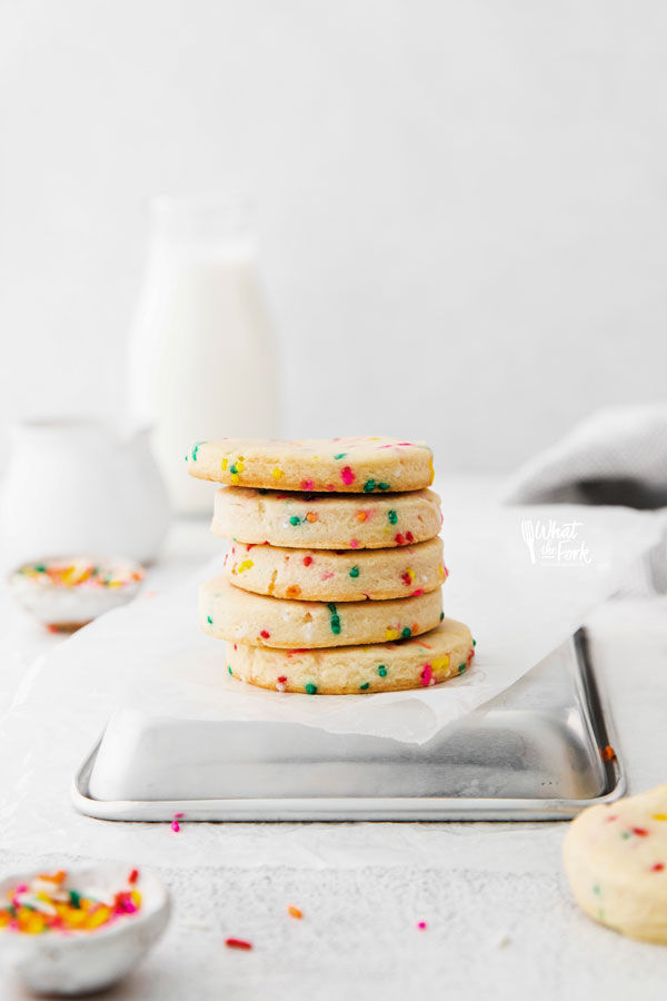 a stack of Gluten Free Shortbread Cookies with Sprinkles on an upside down quarter sheet pan with white parchment paper