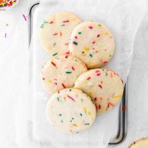 overhead shot of Gluten Free Shortbread Cookies with Sprinkles on a white parchment paper lined quarter sheet pan