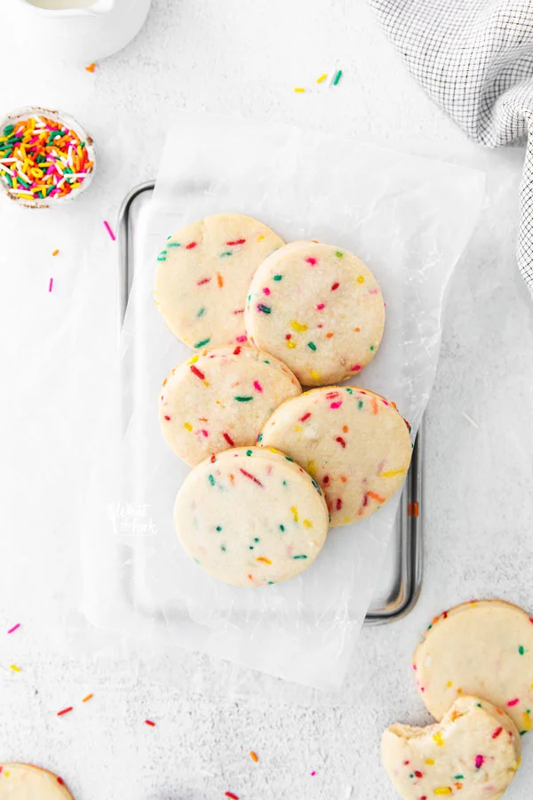 overhead shot of Gluten Free Shortbread Cookies with Sprinkles on a white parchment paper lined quarter sheet pan