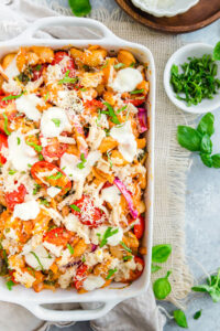 overhead shot of Caprese Pasta Bake Recipe with White Beans in a white casserole dish that's been baked and garnished with fresh basil