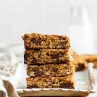 a stack of Gluten Free Oatmeal Chocolate Chip Bars on a small rectangular, wood tray