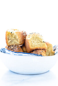 Gluten Free Rolls Recipe with Everything Bagel Seasoning in a white bowl lined with a blue and white striped cloth napkin