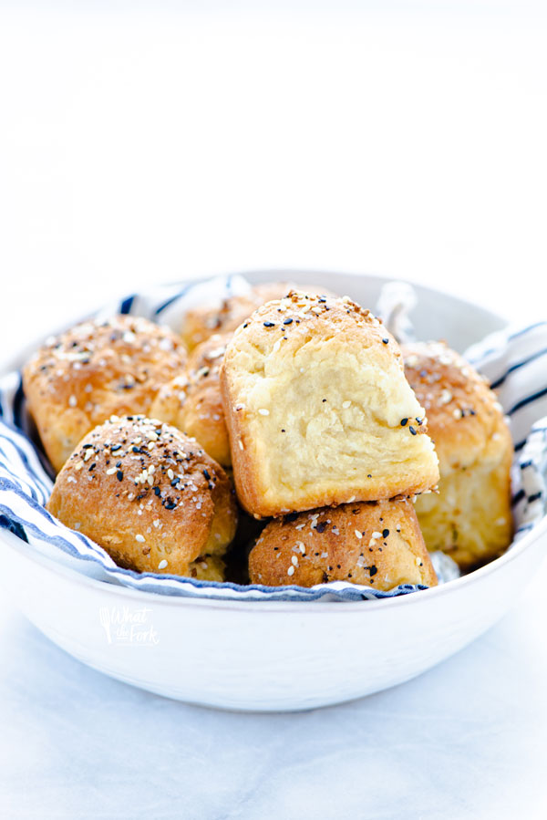 baked Gluten Free Rolls Recipe with Everything Bagel Seasoning in a white bowl lined with a white and blue striped napkin