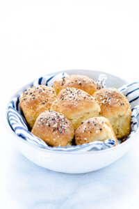 baked Gluten Free Rolls Recipe with Everything Bagel Seasoning in a white bowl lined with a white and navy blue striped cloth napkin