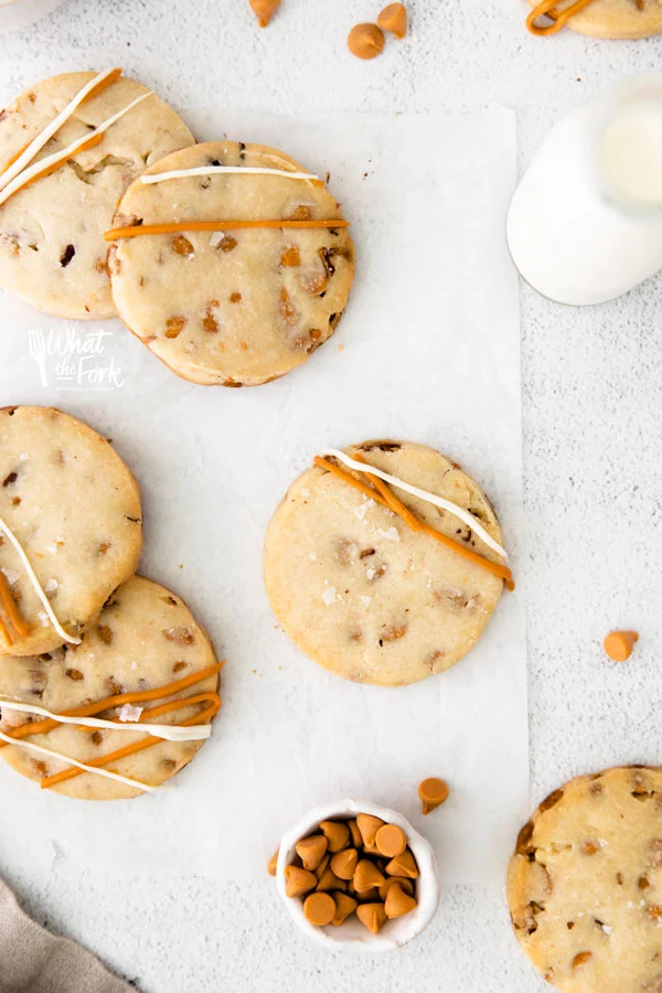 overhead shot of gluten free shortbread cookies on white parchment paper drizzled with melted butterscotch and white chocolate