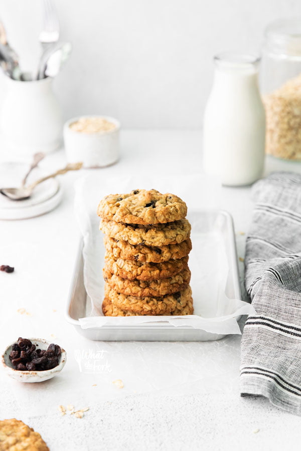 a stack of gluten free oatmeal raisin cookies on a small metal sheet pan lined with white parchment paper