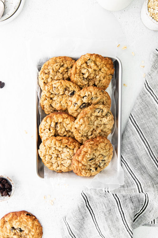 overhead shot of baked gluten free oatmeal raisin cookies lined up on a small silver metal sheet pan