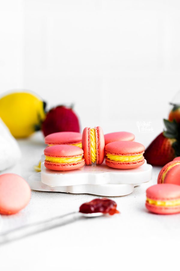 pink Strawberry Lemon Macarons with yellow Lemon Buttercream filling on a white surface