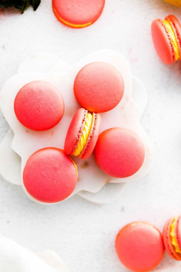 overhead shot of pink Strawberry Lemon Macarons with yellow Lemon Buttercream on a white surface