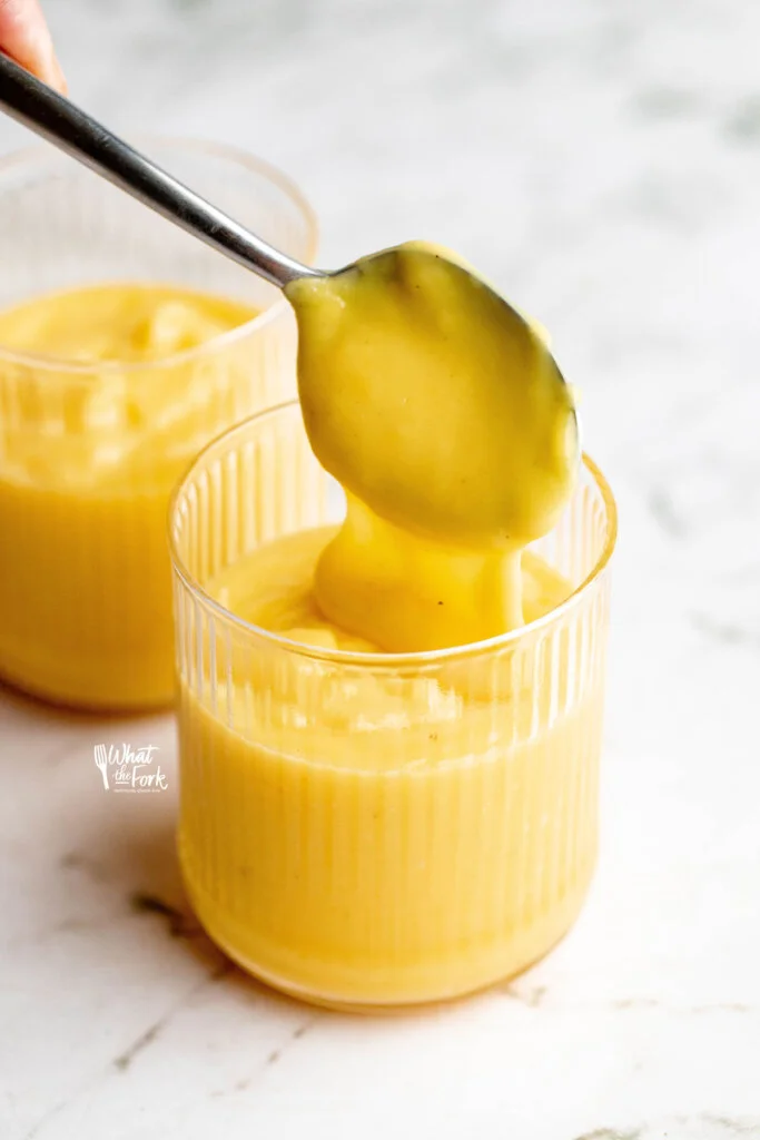cooked lemon pudding being spooned into rimmed glasses
