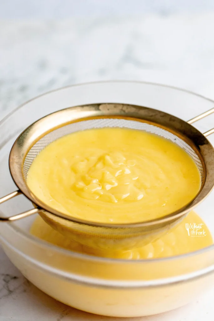 Easy Lemon Pudding Recipe cooked and in a fine mesh strainer over a clear glass bowl