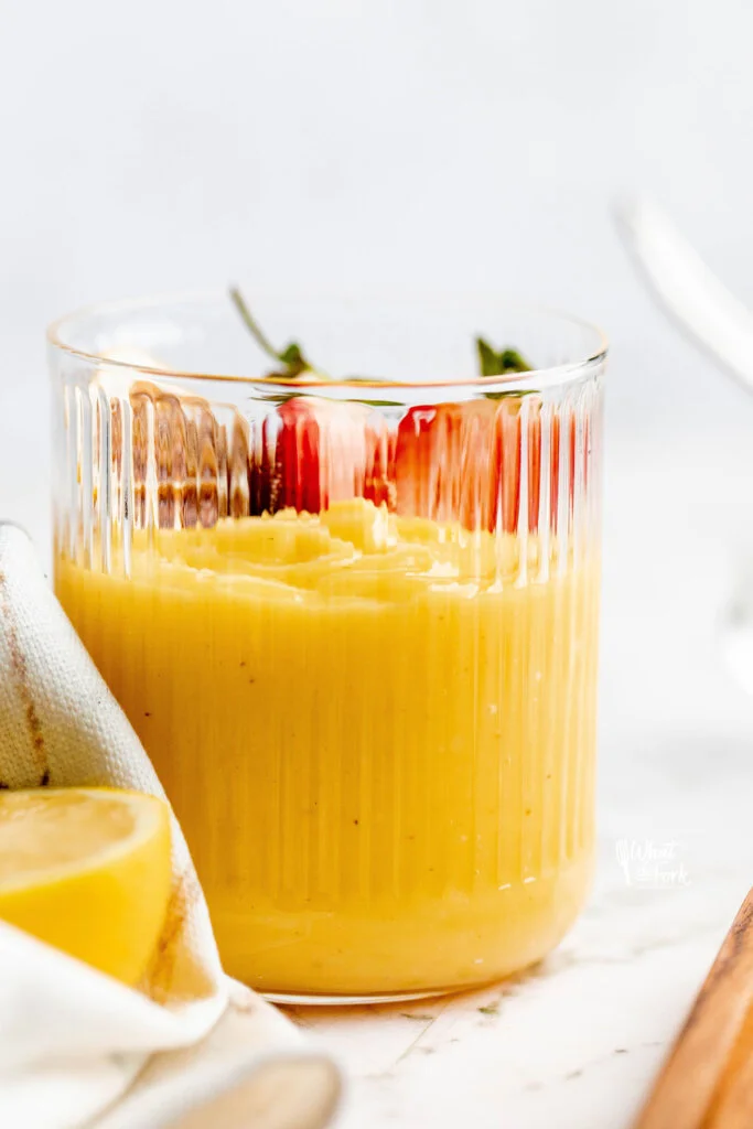 lemon pudding recipe ready to serve in rimmed glasses topped with a fresh strawberry sliced in half