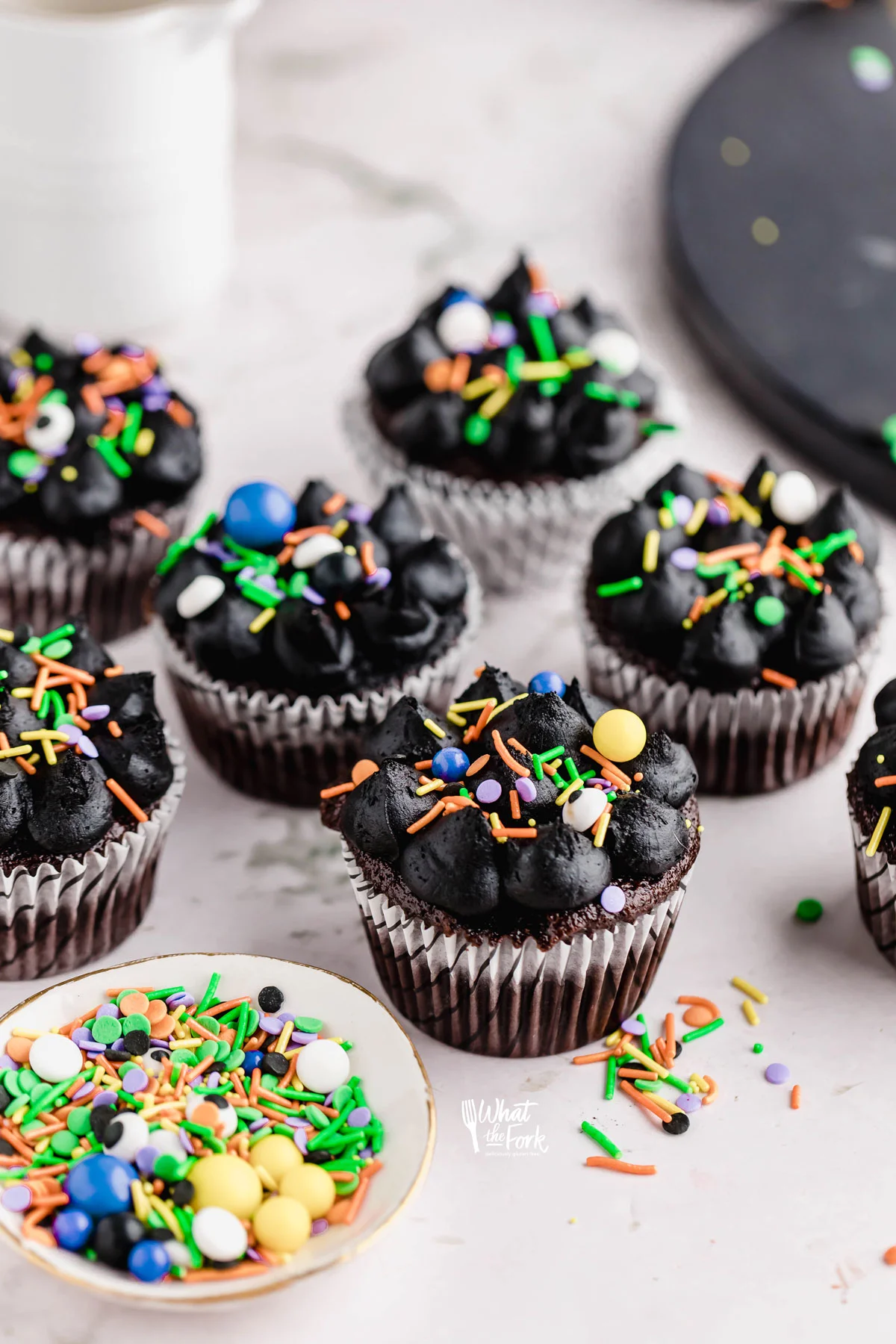 Black Frosting Recipe (American Buttercream) used to decorate chocolate cupcakes in white paper liners that are decorated with Halloween sprinkles