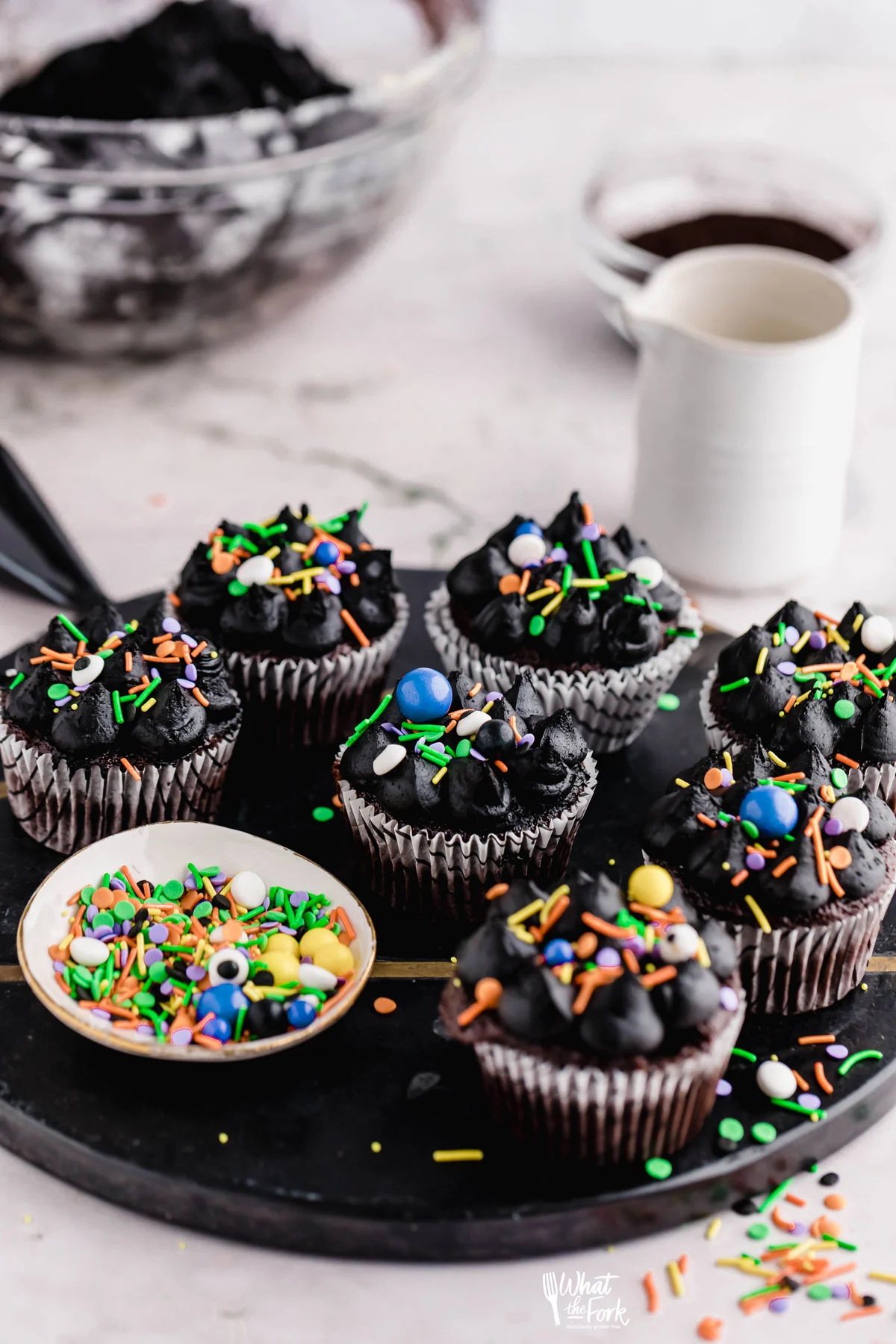 Black Frosting Recipe (American Buttercream) used to decorate chocolate cupcakes that are decorated with Halloween sprinkles on a black serving platter