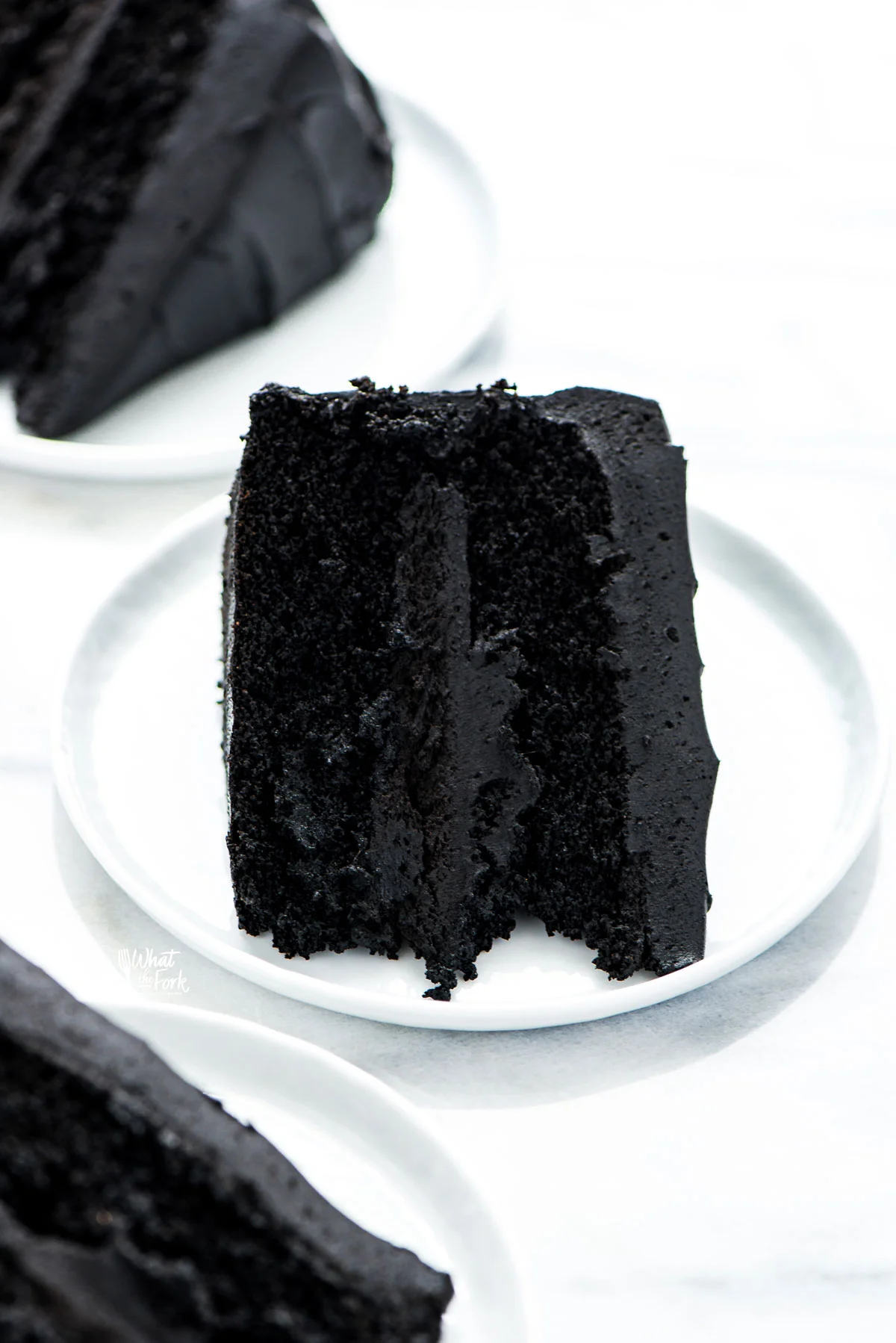 a slice of gluten free black velvet cake on a small round white plate