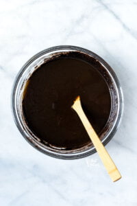 wet and dry ingredients stirred together in a glass bowl with a wood spoon to make a gluten free black velvet cake