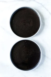 batter for gluten free black velvet cake split between 2 round metal cake pans ready to bake