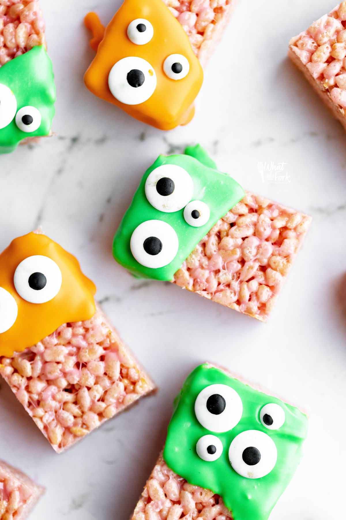 Monster Halloween Rice Krispie Treats dipped in orange and green candy melts and decorated with candy eyes