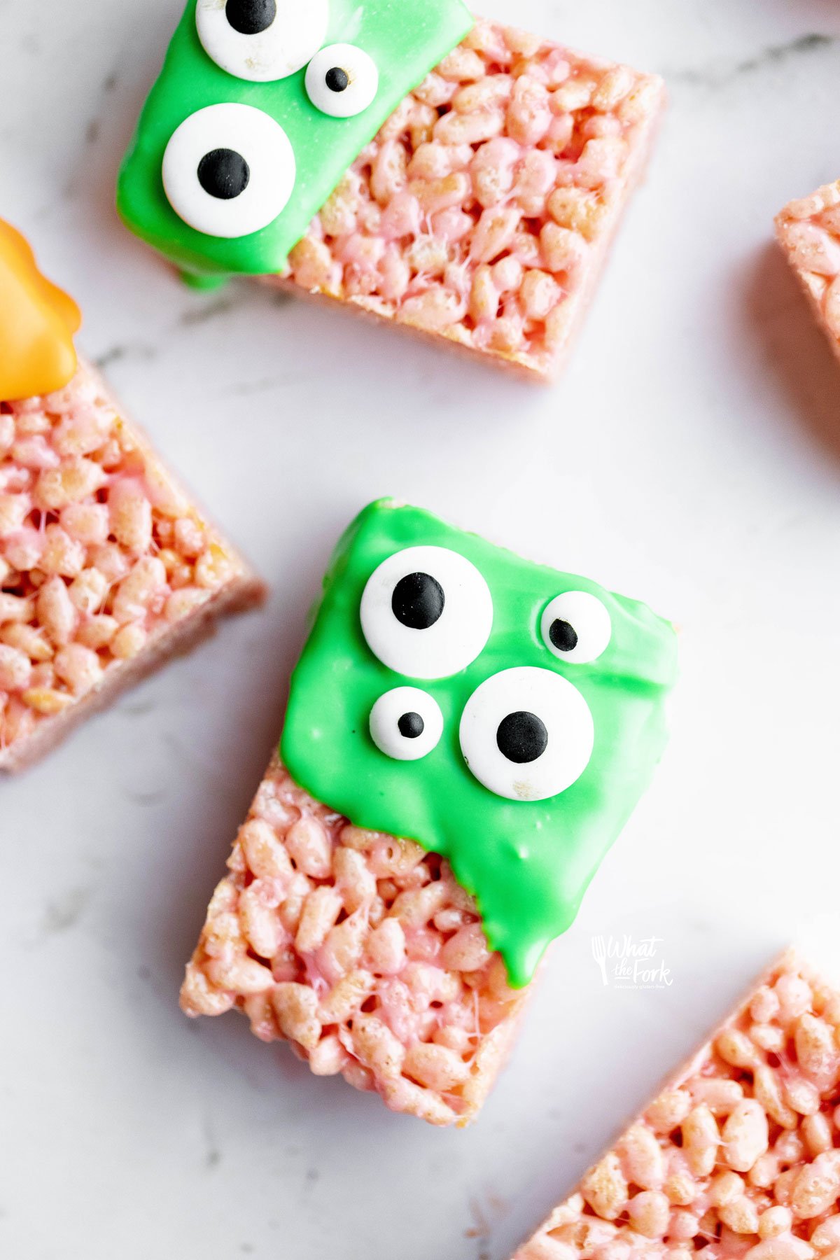 Monster Halloween Rice Krispie Treats dipped in green candy melts and decorated with different sized candy eyes