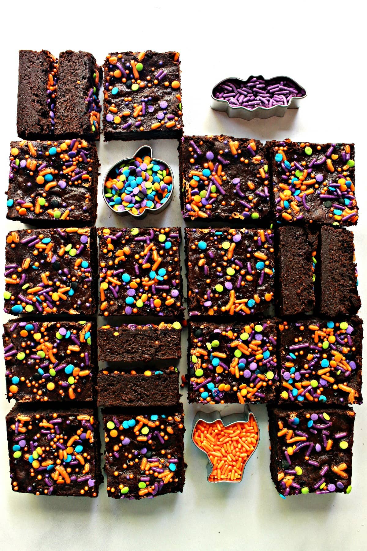 overhead shot of gluten free pumpkin brownies cut and arranged on a white surface with Halloween sprinkles