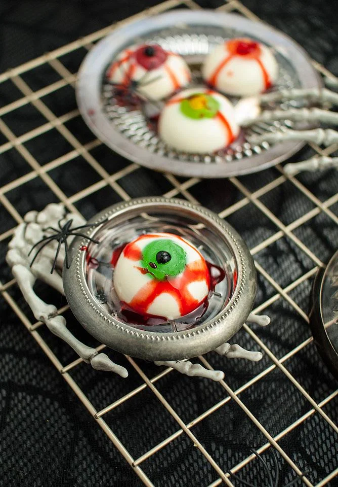 panna cotta  eyes plated on small silver plates on top of skeleton hands